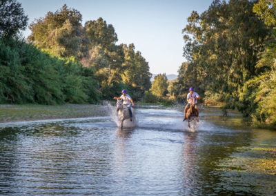Two horse riders riding through a river