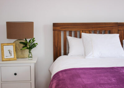 close up of a bed with purple covers next to a bedstand