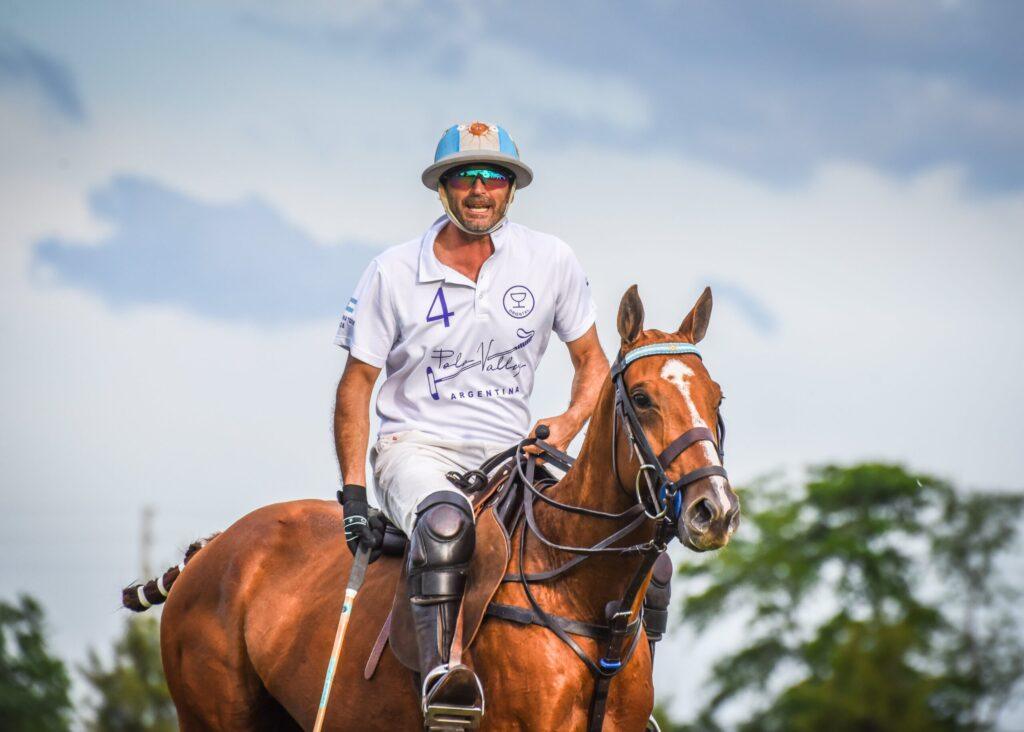 Male polo player in white uniform riding a chestnut horse during a match at a Sotogrande polo event