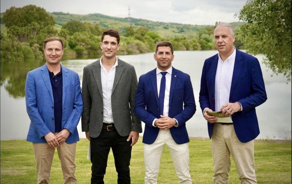 Four men in smart casual attire stand in front of a lake at a Sotogrande investment event, symbolizing leadership and collaboration.