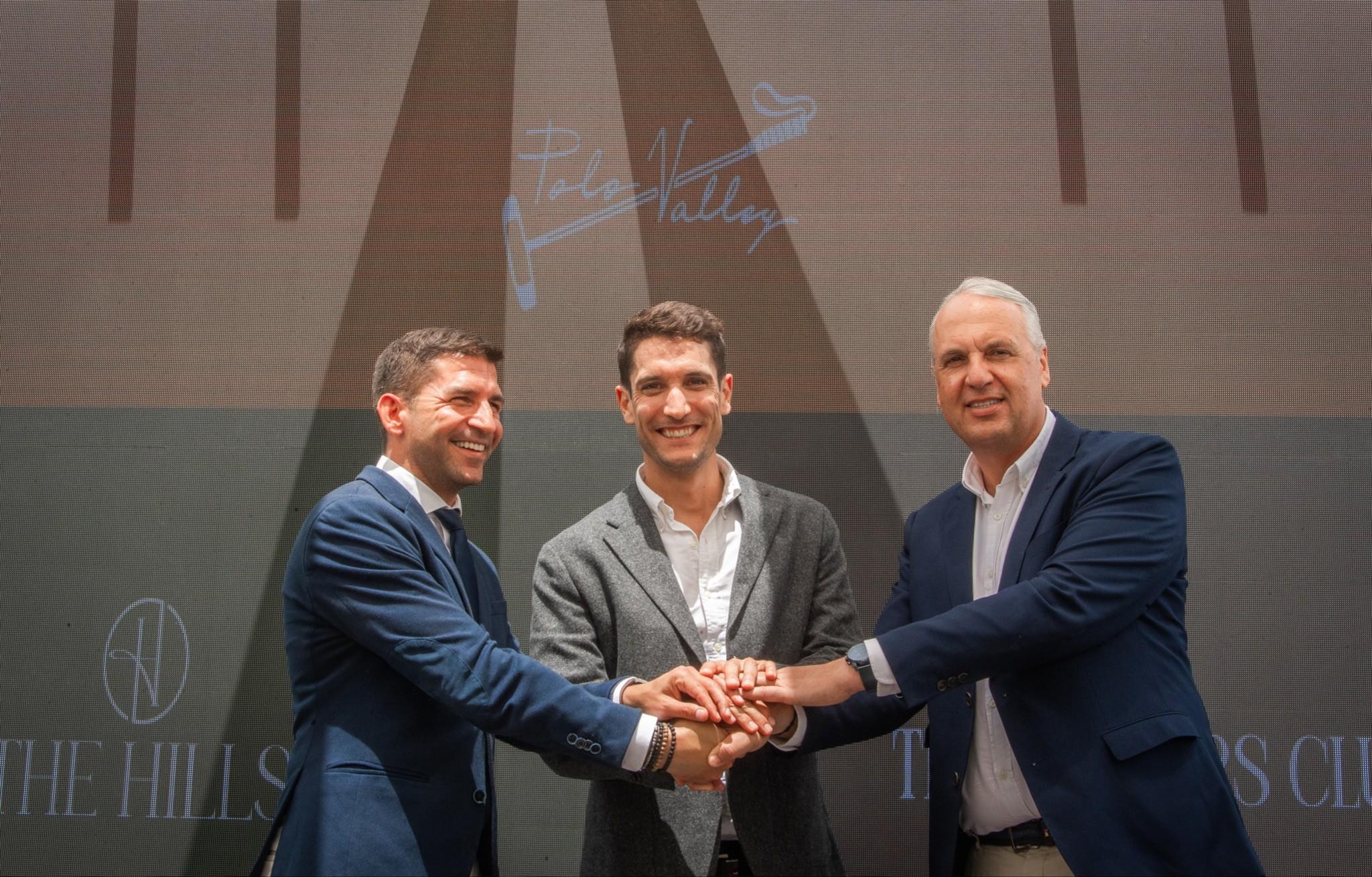 Three men smiling and shaking hands on stage at a Sotogrande investment event, symbolizing partnership between Polo Valley, The Hills, and local authorities.