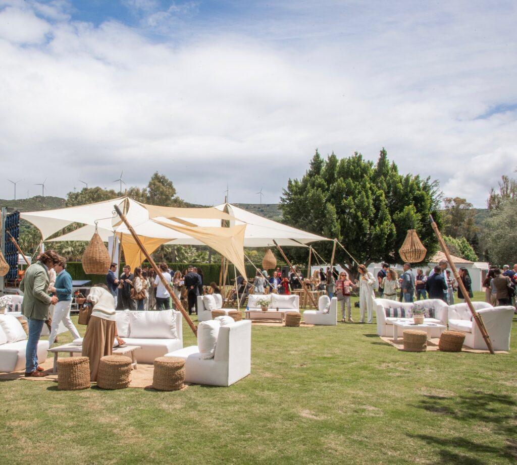 Guests mingle and relax at a stylish outdoor lounge area during a Sotogrande investment event, surrounded by nature and elegant decor.